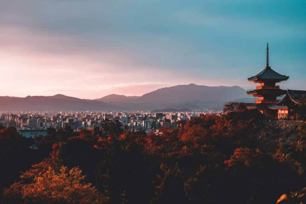 Overview photo of Kyoto in Japan at sunset, bathed in deep orange and reddish colors from the tree leafs and the setting sun