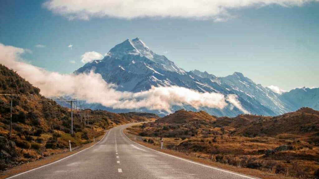 the majestic Mount Cook in New Zealand in the distance with snow covered peaks under the blue sky 