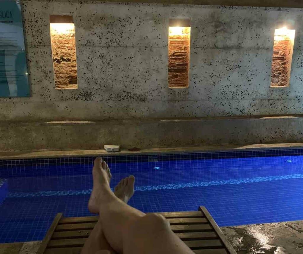 Evening at the hostel in Cartagena, with the blue pool in the courtyard lit from below and the stole wall with warm lighting in the little cracks in the architecture