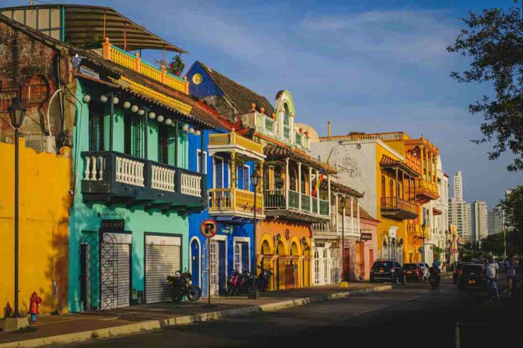 Colorful street in Cartagena Colombia, colonial houses in orange, green and blue with ornate details and balconies. 