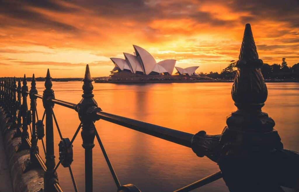 Sydney Opera House seen from across the blank water during a spectacular sunset with bright orange and golden light