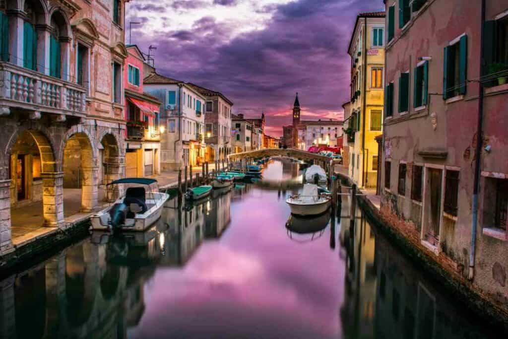 The beautiful calm water in the canals of Venice, Italy, at night with the nights sky above and city lighting around the picturesque town houses