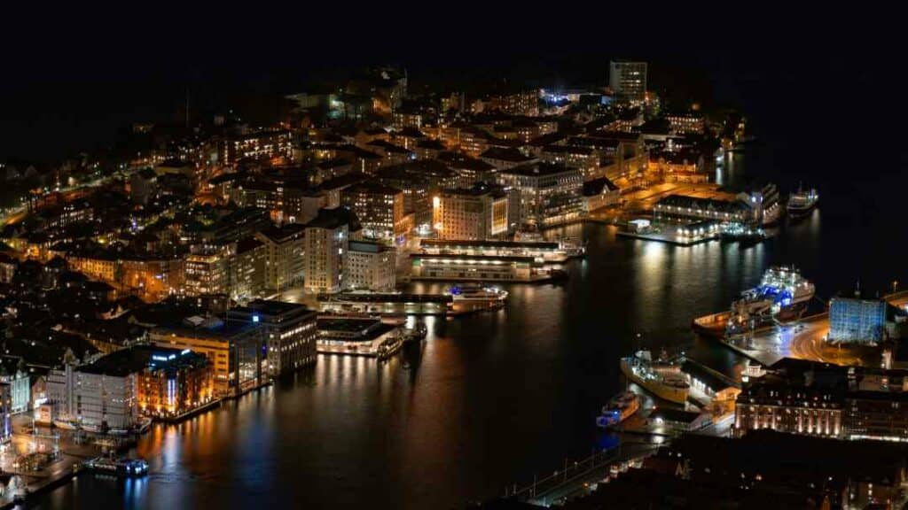 Bergen harbor by night, with the dark water surrounded by boats and buildings lighting up the shores of the port area