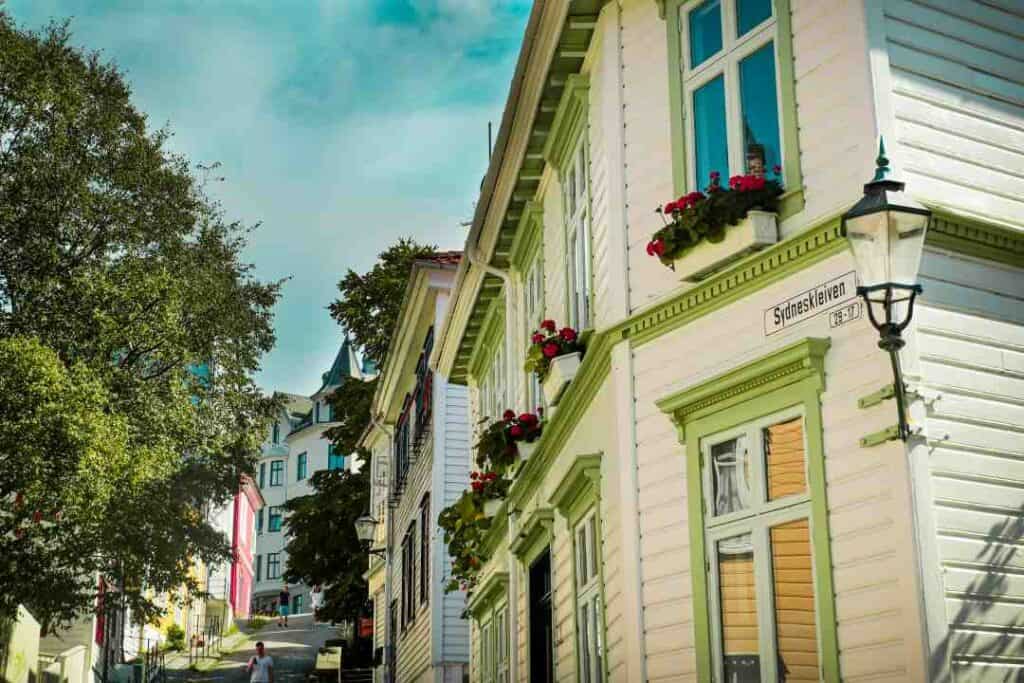 Classic white wooden houses with ornate details and flowers outside the windows in Bergen town, Norway, on a bright sunny summer day