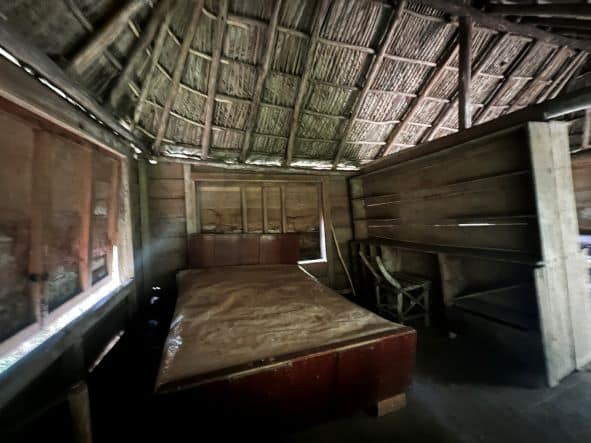 Fidel Castros old clandestine bedroom in the Sierra Maestra, inside a wooden room with no color, the bed is standing in the middle of the room still after 70 years