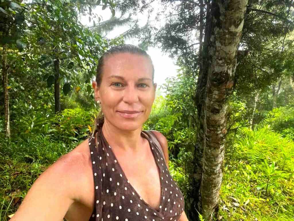 Lady hiking in the rain along a path surrounded by incredibly green lush vegetation in the Blue Mountains in Jamaica during the afternoon rain