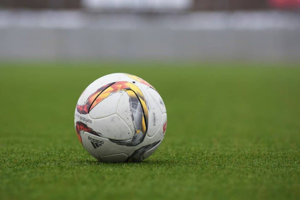 A white football with some colorful patterns on a green grass field