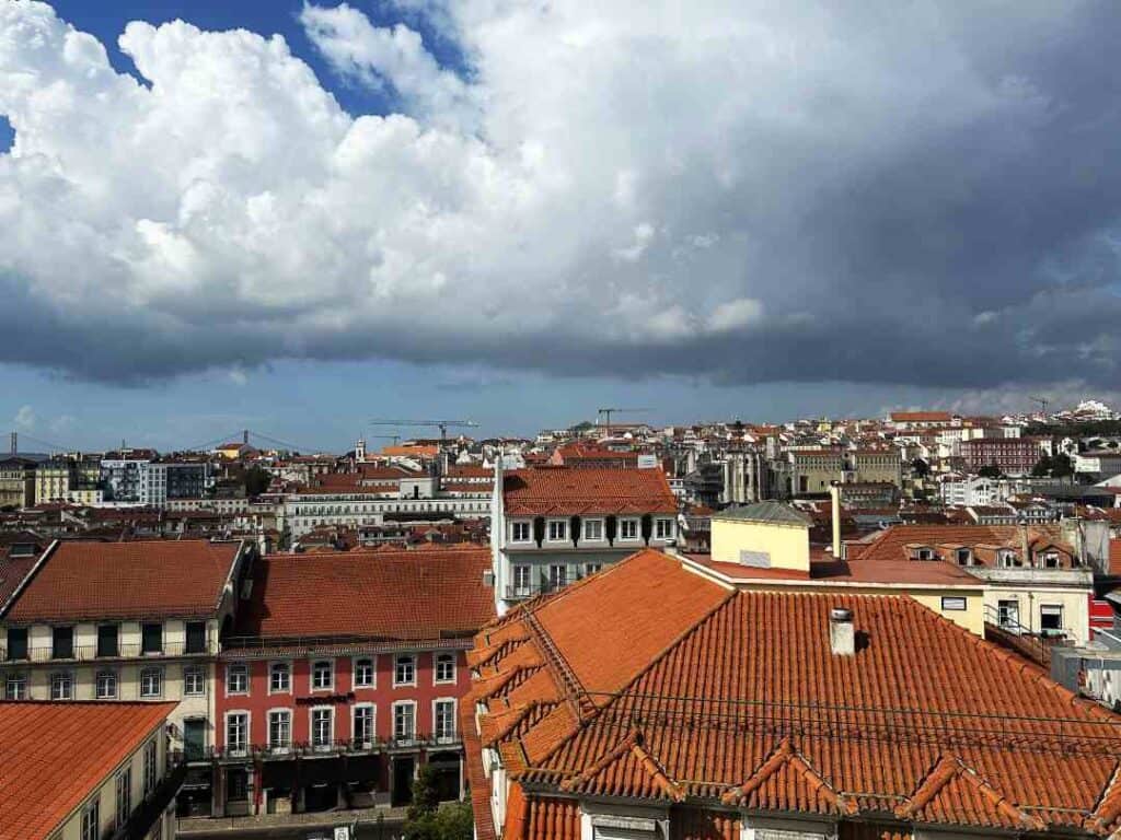 Terracotta colored rooftops stretching wide across a city under a partly cloudy sky