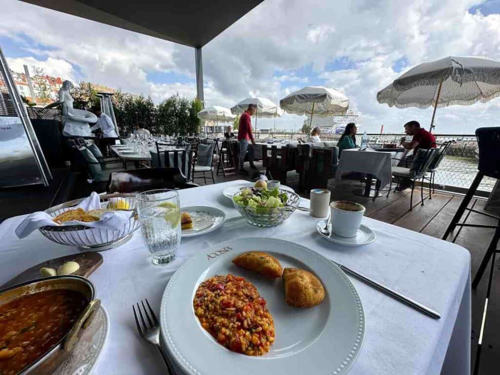 Dinner table with white cloth and with a stunning view of white parasols and a cruise ship in the distance