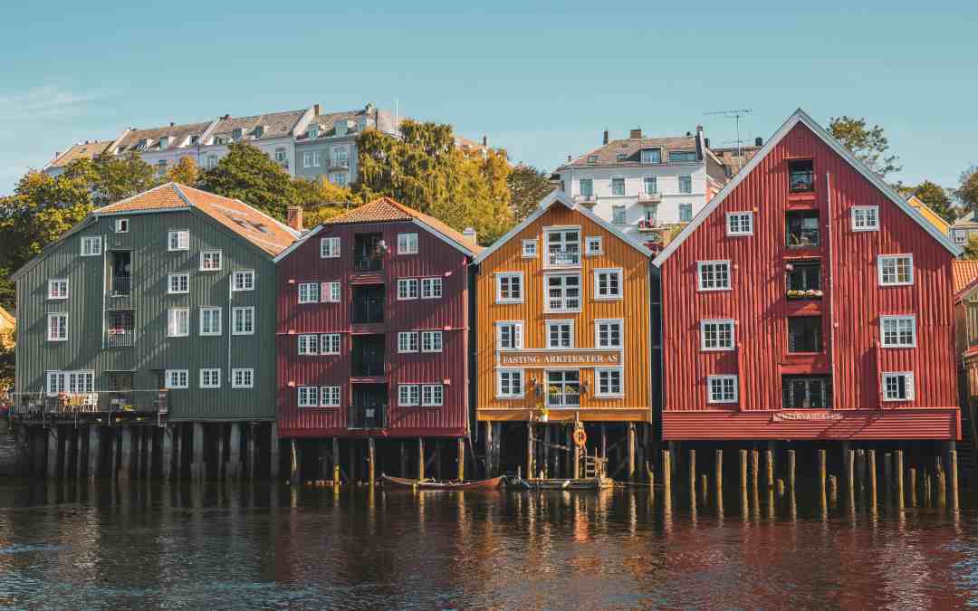 Old colorful wooden houses on a row next to the dark blue water on a sunny summer day