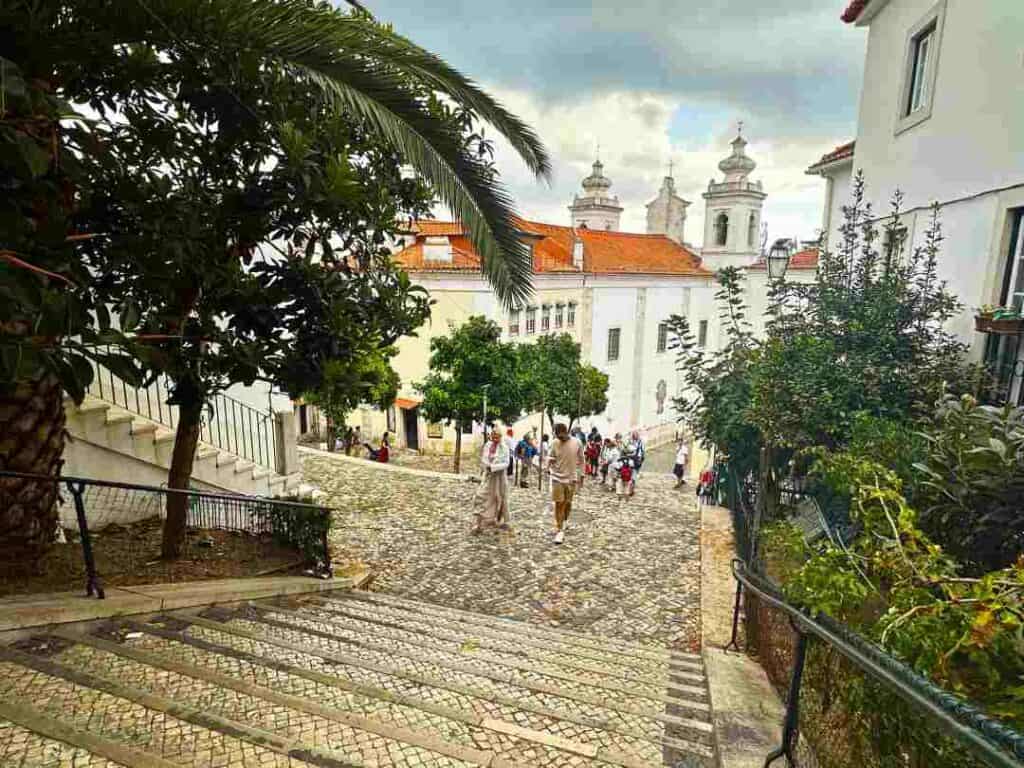 An old tiled stairway in an old city, with cobblestoned terraces, surrounded by colonial houses and greenery