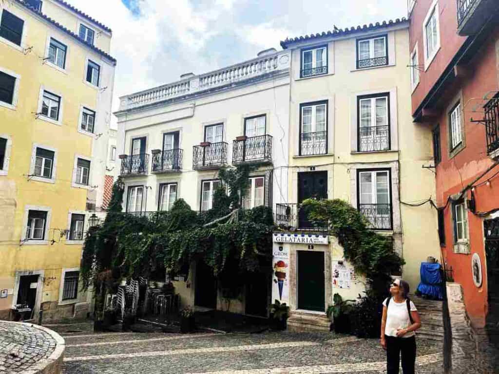 Cobblestoned streets surrounded by colorful colonial buildings with artsy intricate details and greenery on the walls, and a gelateria; an ice cream store! Things to do alone in Lisbon