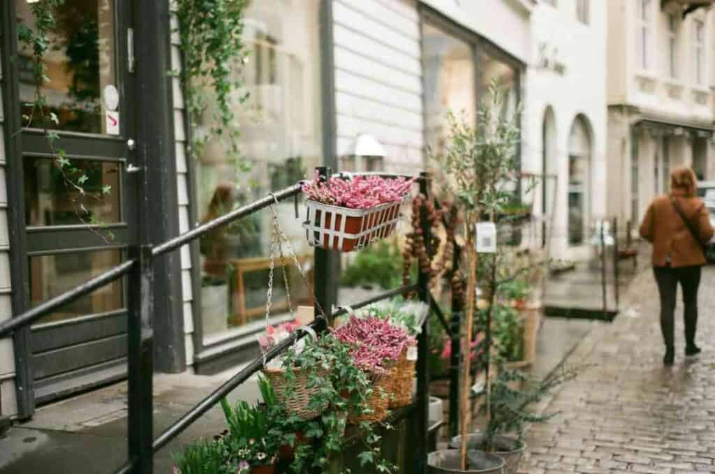 A cobblestoned street and an old fashioned entrance to a building with iron reiling decorated with flowers