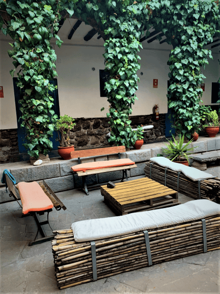 A charming courtyard with seating ant tables, surrounded by old stone walls and greenery