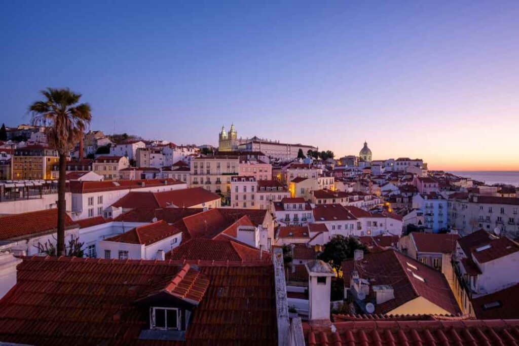 Overview photo of a city at sunrise with the cold but glowing light hitting the white buildings and rooftops under a pale blue sky