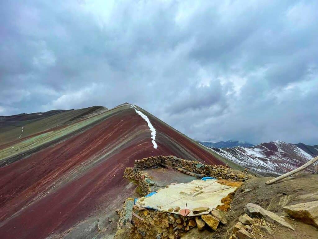 A colorful mountain with a spectre of red, orange, purple and green under a cloudy sky