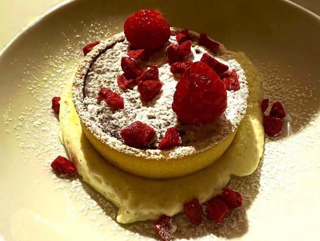 Pastry with custard, rasberries and white sweet flour on top looking super delicious