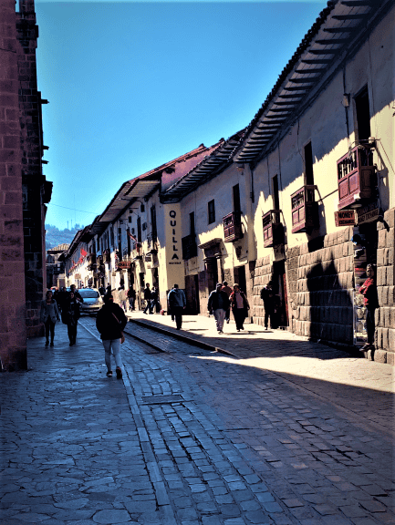 An old cobblestioned street wurrounded by old stone buildings in a mountain town on a sunny day