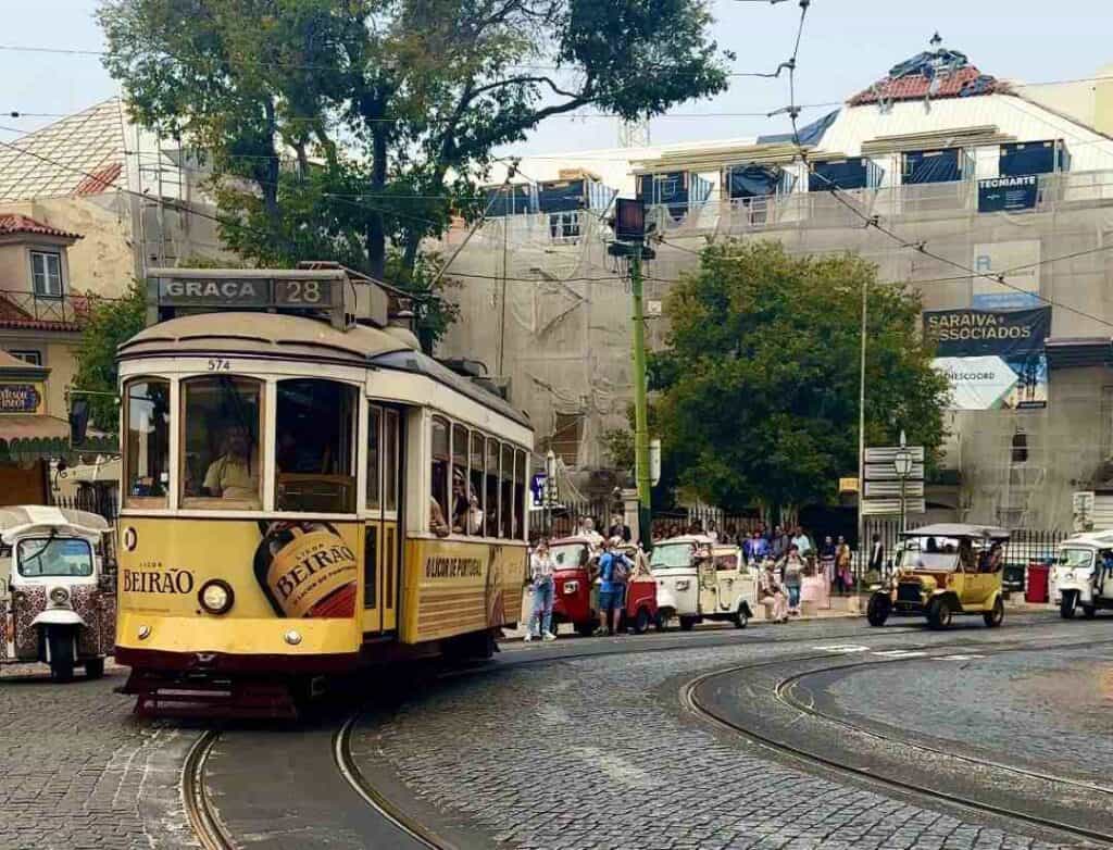 A yellow tram driving through a city on curved trails