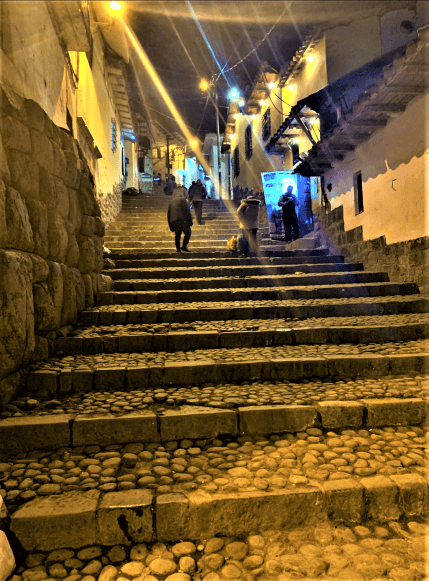 Old cobbled stone stairs encircled by old stone buildings at night