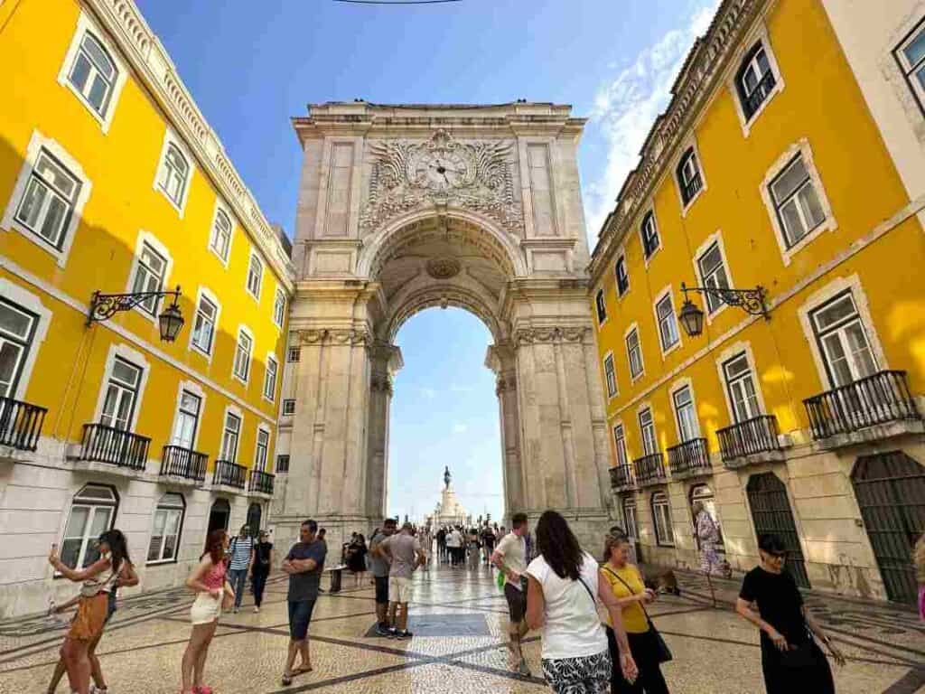 A bright yellow archway at the end of a tiled city street on a summer day