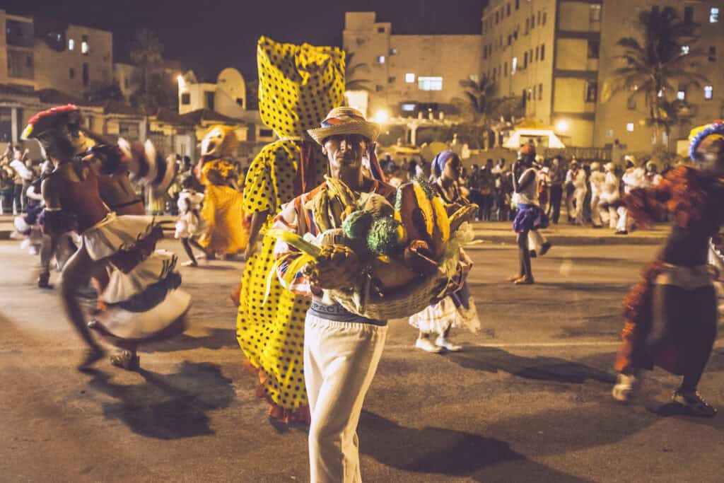 People with colorful costumes dancing on a square at night