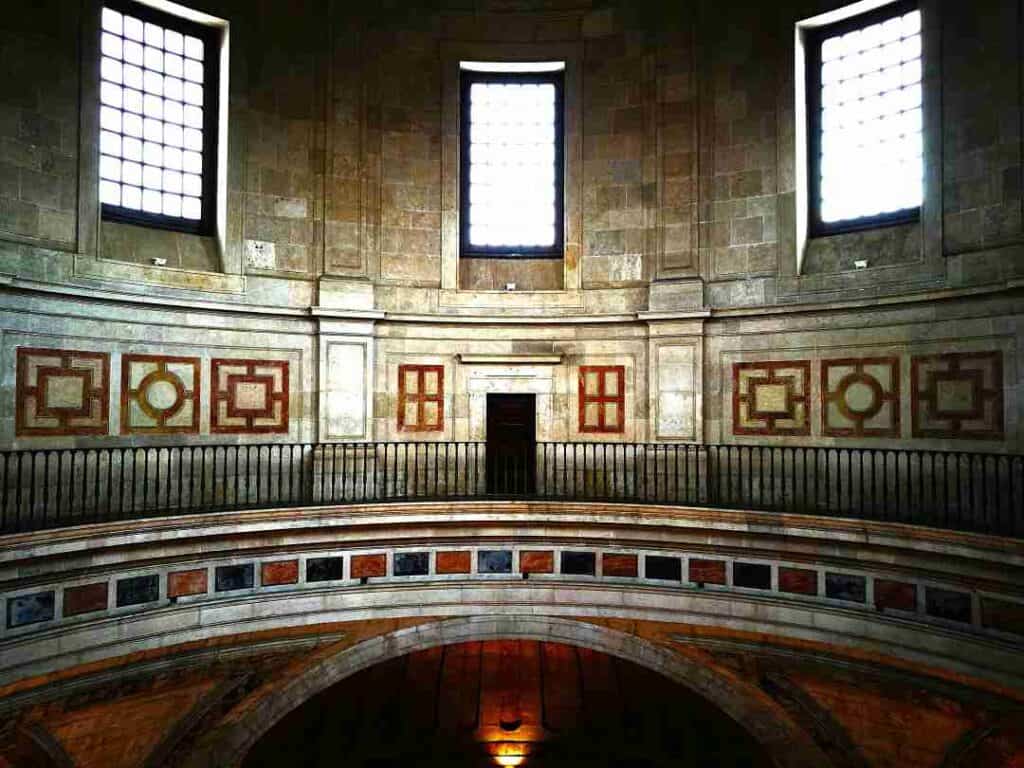 An old celestian building with windows letting in bright light, and stone art details in a circular shaped dome structure