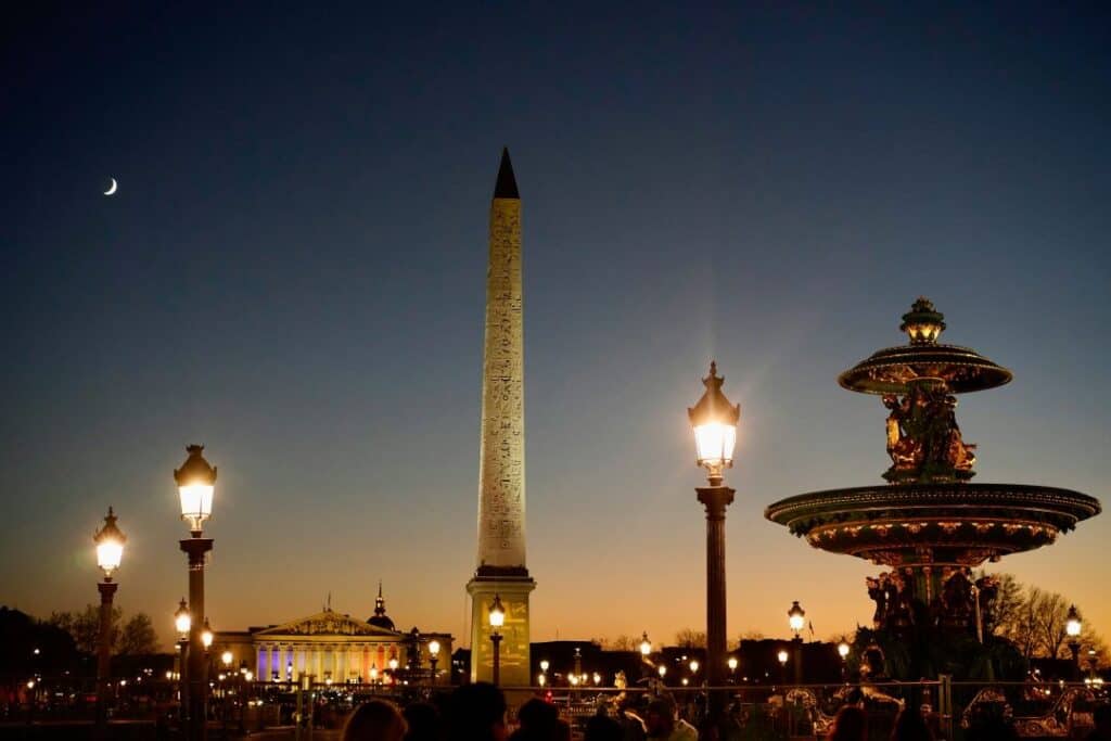 A large beautiful square at night under a dark deep blue sky with elegant lighting and monuments 