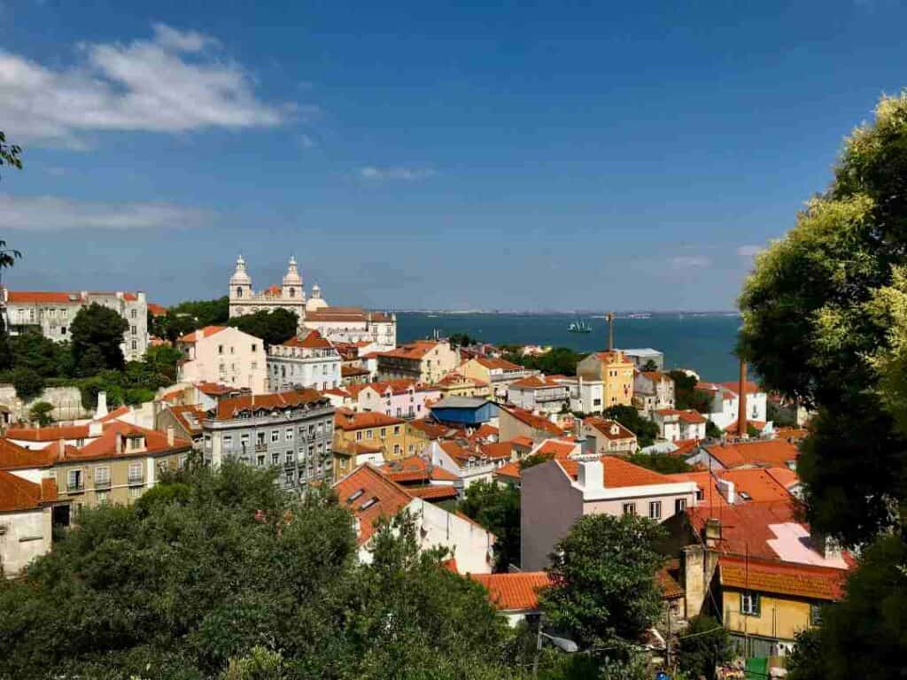 White old buildings with maroon terracotta roofs in front of a deep blue sea under the blue sky