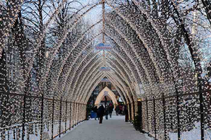 A pedestrian light tunnel on a winter day, the ground is covered with white snow and the light outside is bluish and pale