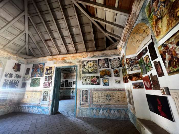 the inside of a beautiful old building filled with art on the walls, with an ornate high ceiling, and murals painted directly on the walls