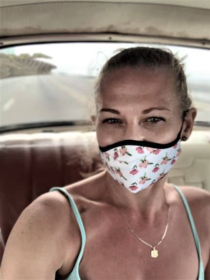 Woman with a facemask in the back seat of a classic american car